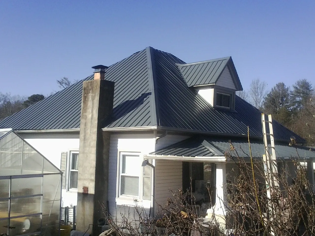 Dark blue standing seam metal roof on a white farmhouse with dormer — Slate & Tile Roof Repair by Roofing Brothers in Black Lick
