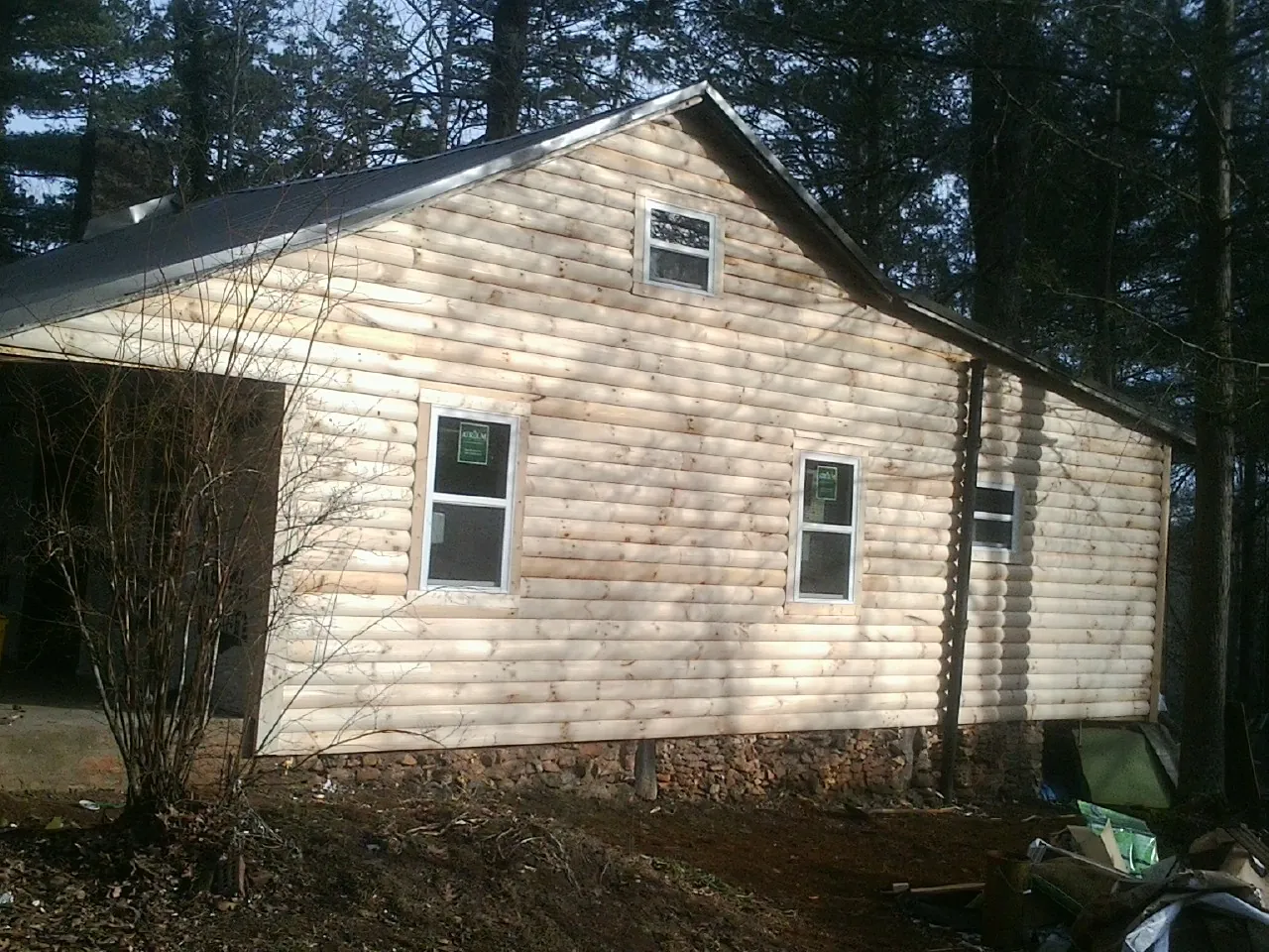 New log siding and dark metal roofing on a gable end in Black Lick
