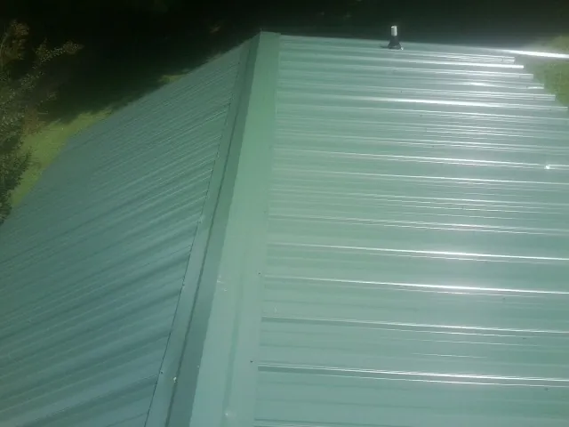 New green metal panels meeting at the ridge of a roof — Flat Roof Repair work by our crew in Black Lick