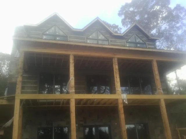 Dormers and porch framing on a large log home under construction — Roof Coating work by our crew in Black Lick