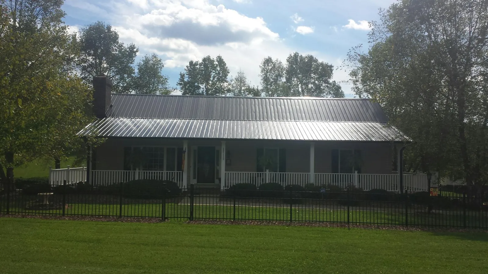 Gray metal roof on a brick ranch with a full width front porch — Gutter Guard Installation work by our crew in Black Lick