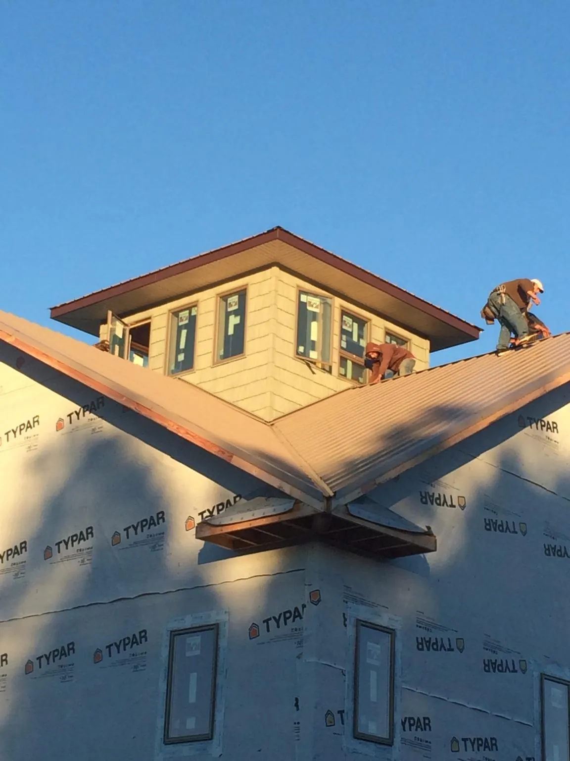 Roofers working around a rooftop cupola on a new metal roof at sunset — Roof Waterproofing in Black Lick by Roofing Brothers